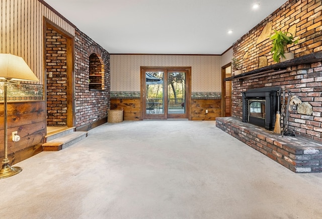 living room featuring brick wall, wooden walls, carpet flooring, and a brick fireplace