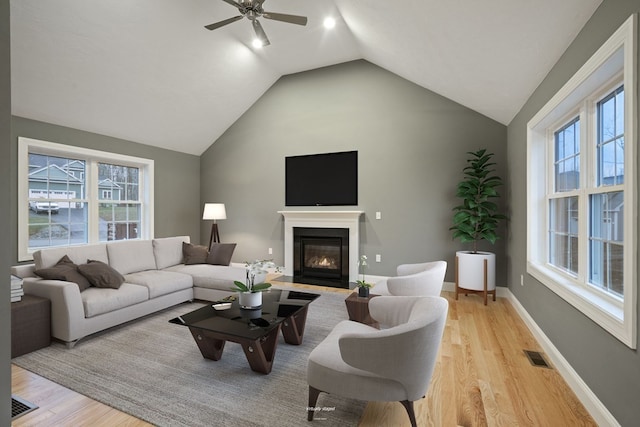 living room with light hardwood / wood-style floors, lofted ceiling, a wealth of natural light, and ceiling fan