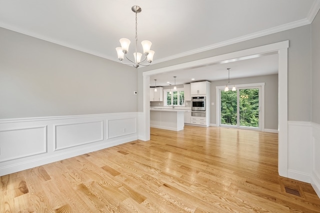 interior space featuring ornamental molding, a chandelier, and light hardwood / wood-style flooring