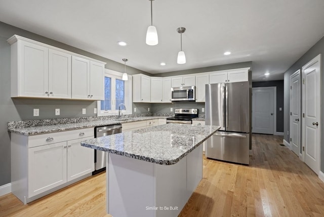 kitchen featuring stainless steel appliances, light wood-type flooring, a kitchen island, and white cabinets