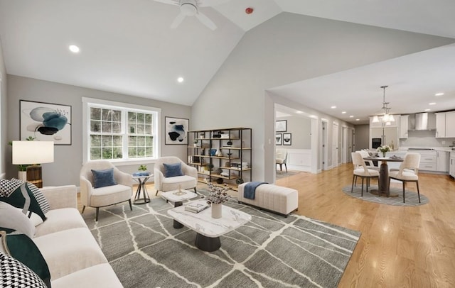 living room featuring ceiling fan, high vaulted ceiling, and light hardwood / wood-style flooring