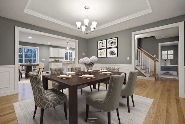 dining area featuring light hardwood / wood-style flooring, a tray ceiling, and crown molding