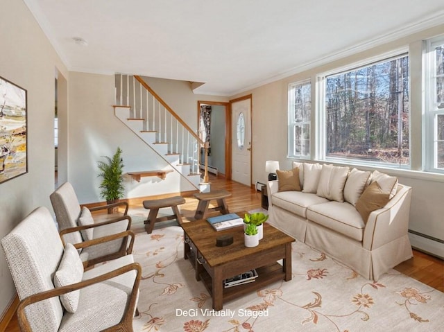 living room with baseboard heating, light hardwood / wood-style floors, and ornamental molding