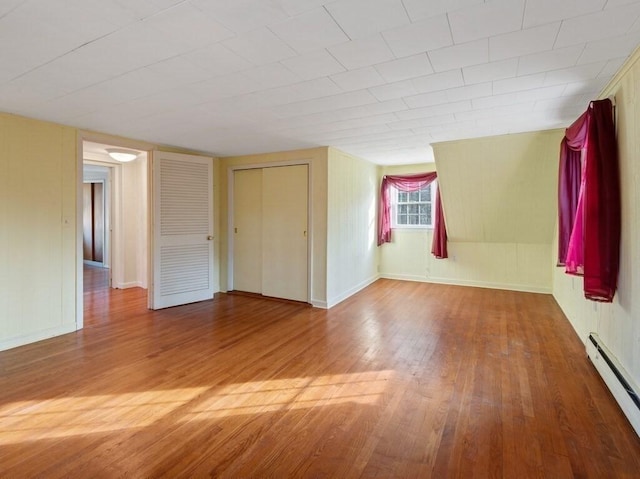 empty room with hardwood / wood-style floors and a baseboard radiator