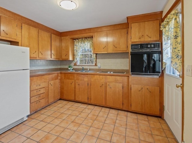 kitchen with backsplash, sink, black oven, white fridge, and stovetop