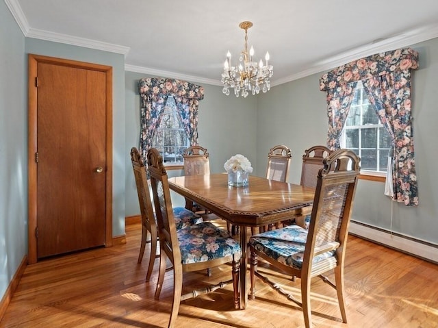 dining space with light wood-type flooring, ornamental molding, and an inviting chandelier