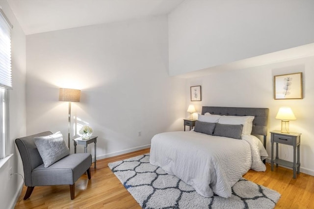 bedroom with vaulted ceiling and light wood-type flooring