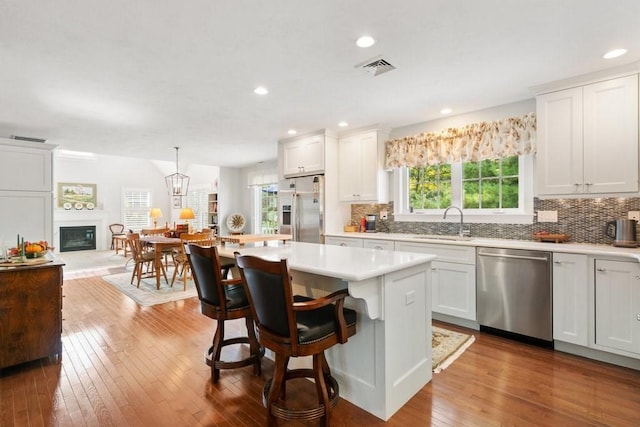 kitchen featuring sink, white cabinets, decorative light fixtures, a kitchen island, and appliances with stainless steel finishes