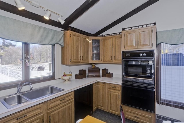 kitchen with a sink, black appliances, vaulted ceiling, light countertops, and glass insert cabinets