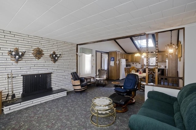 carpeted living room with a brick fireplace, brick wall, an inviting chandelier, and vaulted ceiling