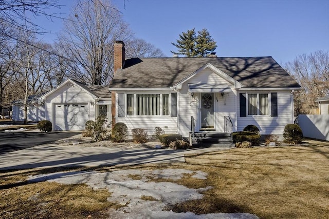 view of front of house featuring driveway, a chimney, an attached garage, and fence