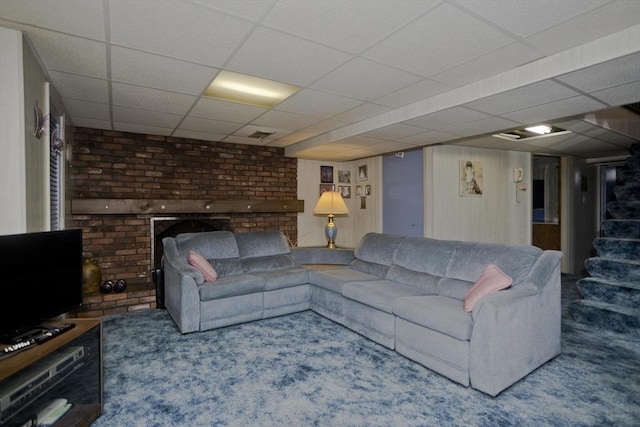 living area featuring carpet flooring, a fireplace, stairs, and a paneled ceiling