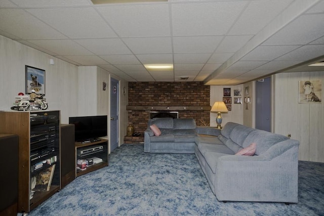 living area with a paneled ceiling, carpet floors, and wood walls