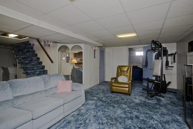 carpeted living area with arched walkways, stairway, a fireplace, and a paneled ceiling