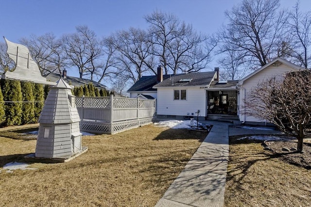 rear view of property featuring a yard, a wooden deck, and a chimney