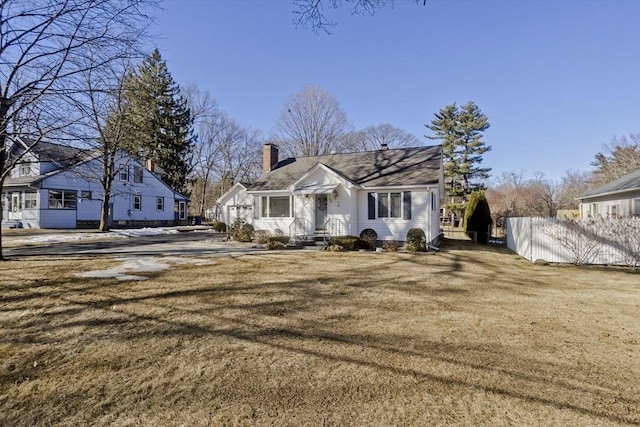 view of front of property with a chimney, a front lawn, and fence