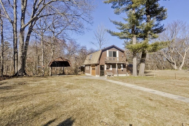 view of front of property with a gambrel roof, a balcony, and dirt driveway