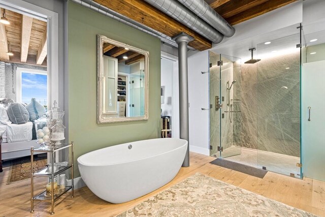 bathroom with a wood stove, separate shower and tub, wood-type flooring, and beam ceiling