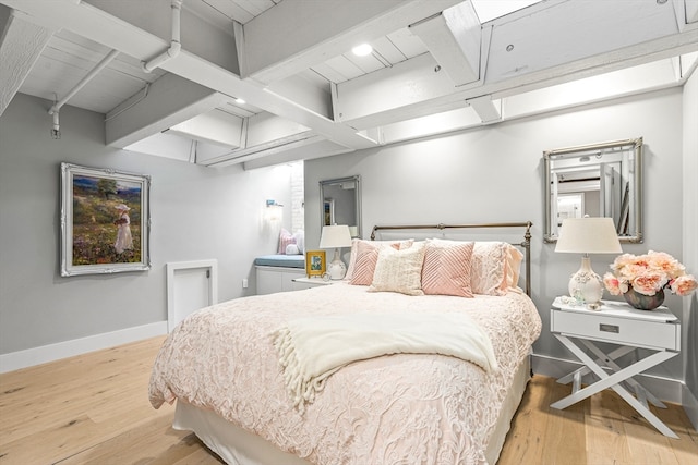 bedroom with light wood-type flooring and beam ceiling