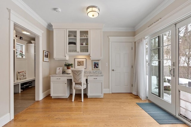 office area with baseboards, ornamental molding, built in study area, and light wood-style floors