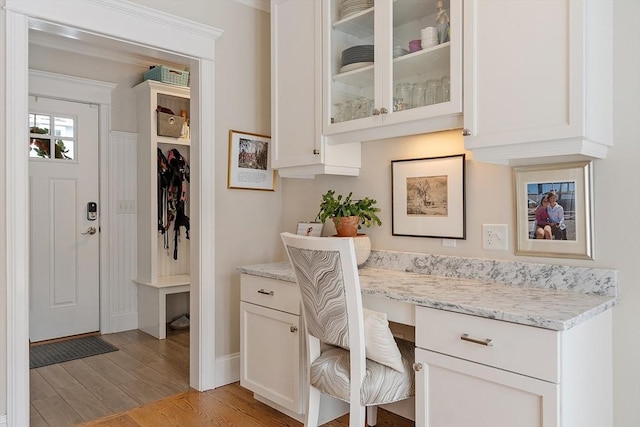 office space with light wood finished floors, built in desk, and baseboards