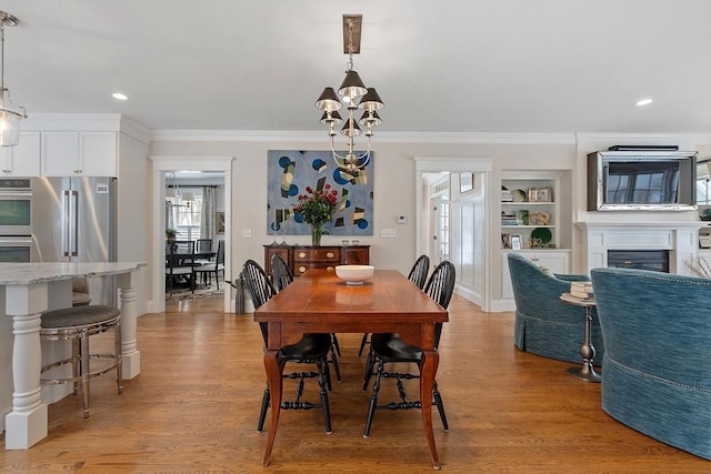 dining space with light wood-style flooring, a fireplace, and ornamental molding