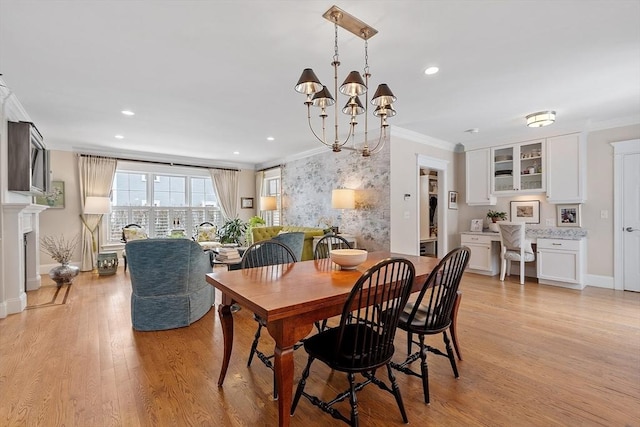 dining space with a chandelier, light wood-style flooring, recessed lighting, a fireplace, and crown molding