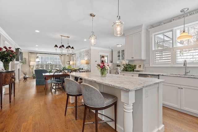 kitchen featuring hanging light fixtures, a kitchen island, white cabinetry, and a sink