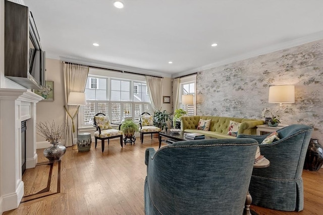 living area with ornamental molding, a fireplace, light wood-style flooring, and wallpapered walls