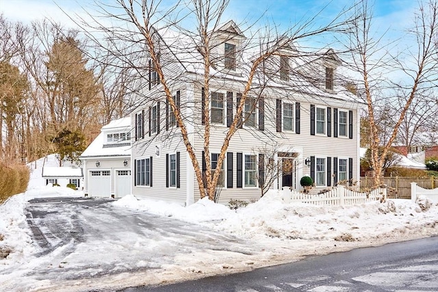 colonial-style house featuring a garage and fence