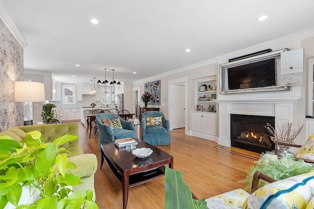 living area with ornamental molding, a fireplace with flush hearth, light wood finished floors, and recessed lighting