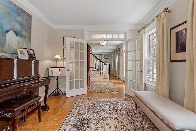 entryway featuring baseboards, french doors, stairway, light wood-type flooring, and crown molding