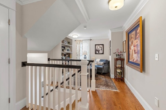 hall with ornamental molding, baseboards, light wood-style flooring, and an upstairs landing