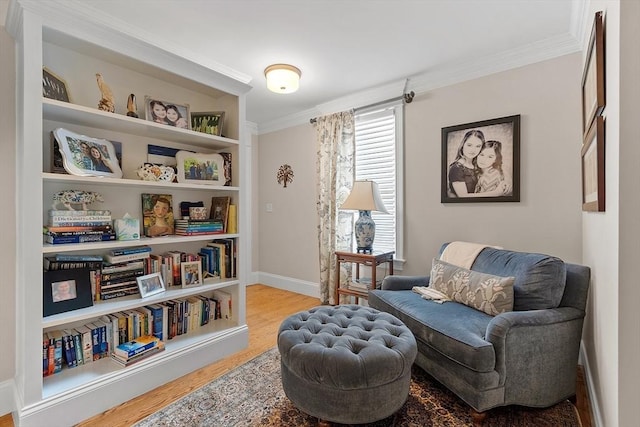 living area with baseboards, light wood-style flooring, and crown molding