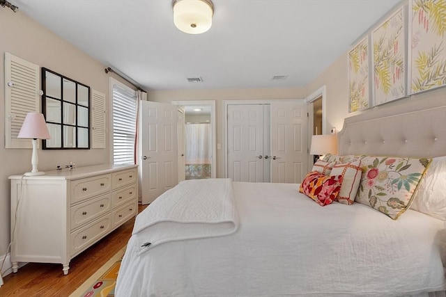 bedroom featuring light wood-style floors, visible vents, and a closet