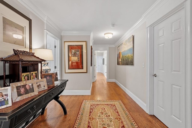 corridor featuring ornamental molding, light wood-style flooring, and baseboards