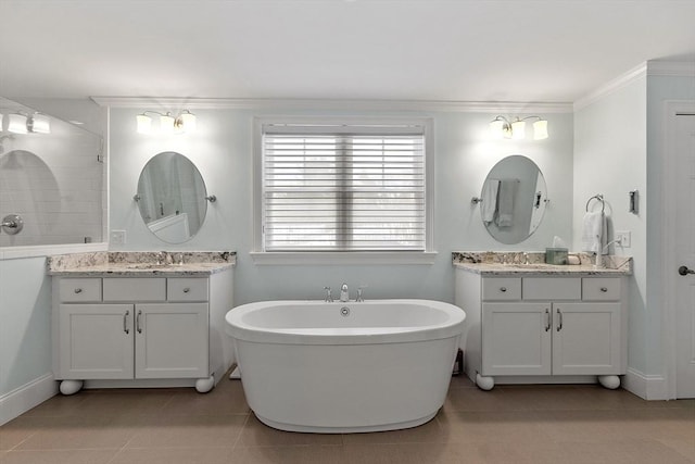 full bath featuring a freestanding tub, tile patterned flooring, two vanities, and a sink