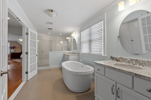 ensuite bathroom with a stall shower, visible vents, a soaking tub, ornamental molding, and a sink