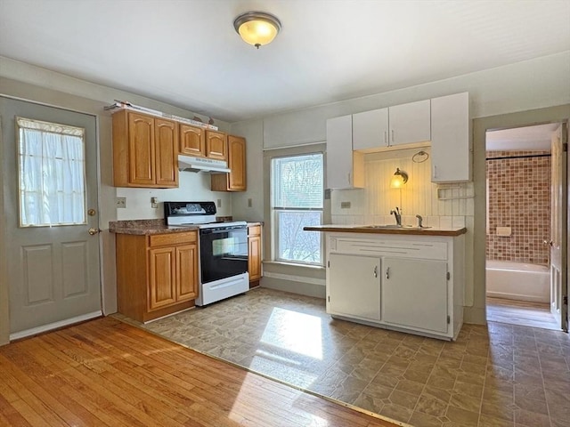 kitchen featuring electric stove, sink, light hardwood / wood-style flooring, and white cabinets