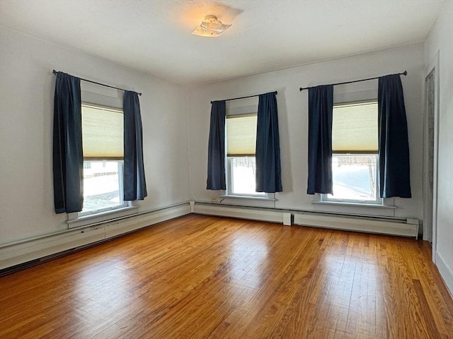 empty room with hardwood / wood-style flooring and baseboard heating