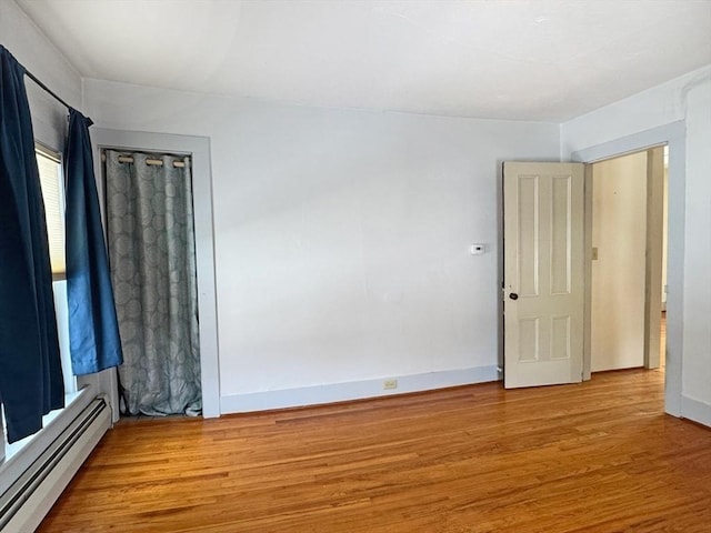 empty room with a baseboard radiator and light hardwood / wood-style floors