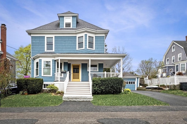 traditional style home with a porch, a shingled roof, and fence