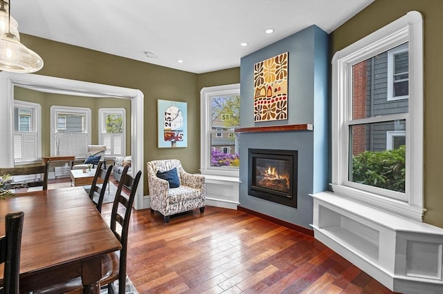 living area with recessed lighting, baseboards, a glass covered fireplace, and wood finished floors