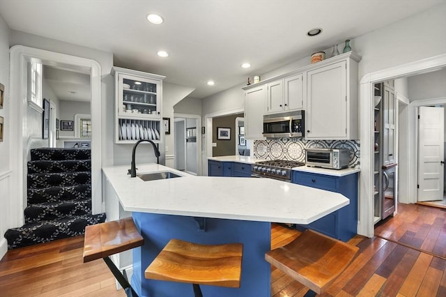 kitchen featuring a sink, a breakfast bar, dark wood finished floors, blue cabinetry, and appliances with stainless steel finishes