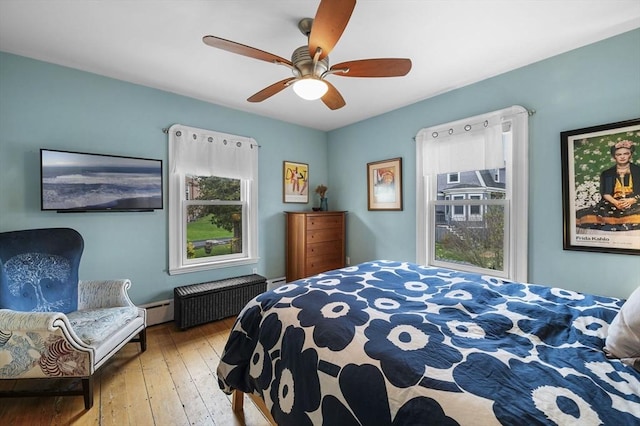 bedroom featuring ceiling fan, a baseboard radiator, and wood-type flooring