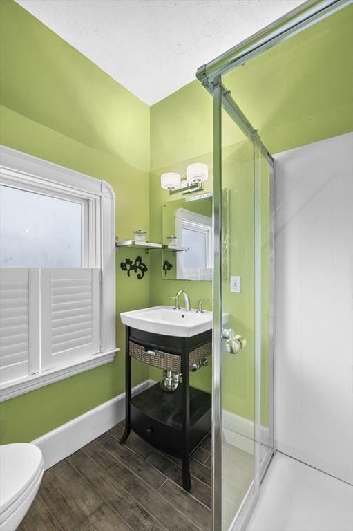 full bath with a shower stall, baseboards, toilet, and wood finished floors