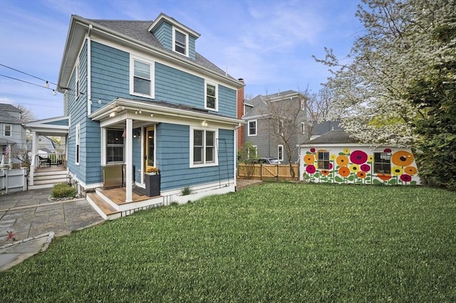 back of property with a yard, fence, and a porch