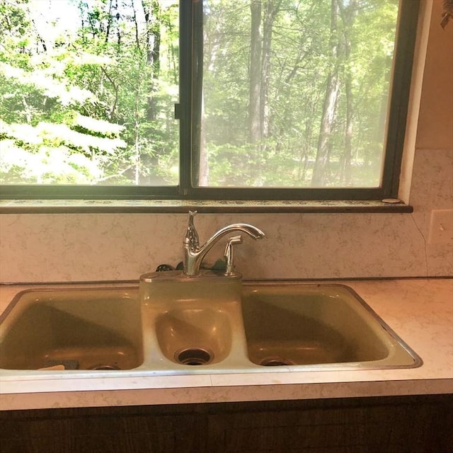 kitchen view of a sink, light countertops, and tasteful backsplash