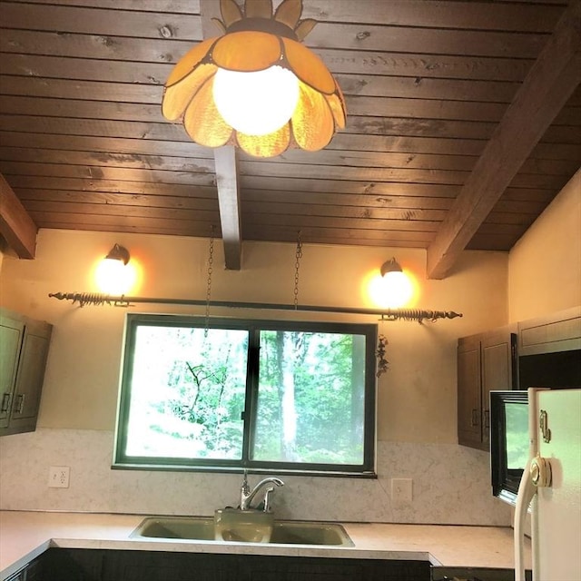 kitchen with wood ceiling, beamed ceiling, fridge, light countertops, and a sink