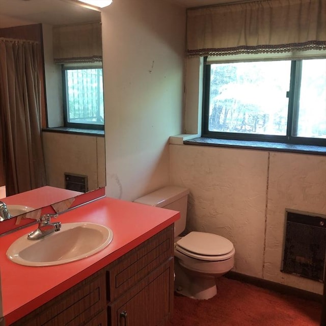 bathroom featuring plenty of natural light, toilet, vanity, and heating unit